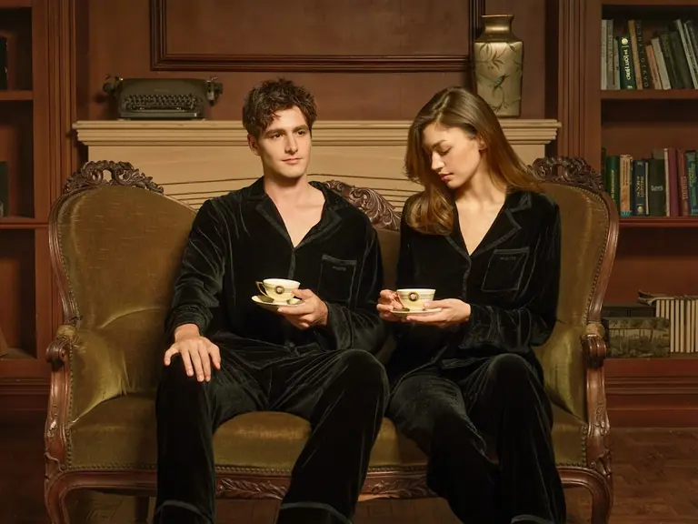 Couple in black pajamas drinking tea on a sofa