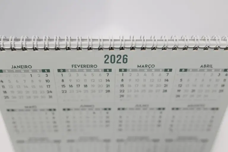 Close-up of a 2026 spiral-bound desk calendar with months in Portuguese.