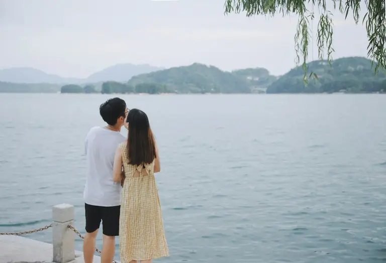 man beside woman in yellow dress beside body of water during daytime