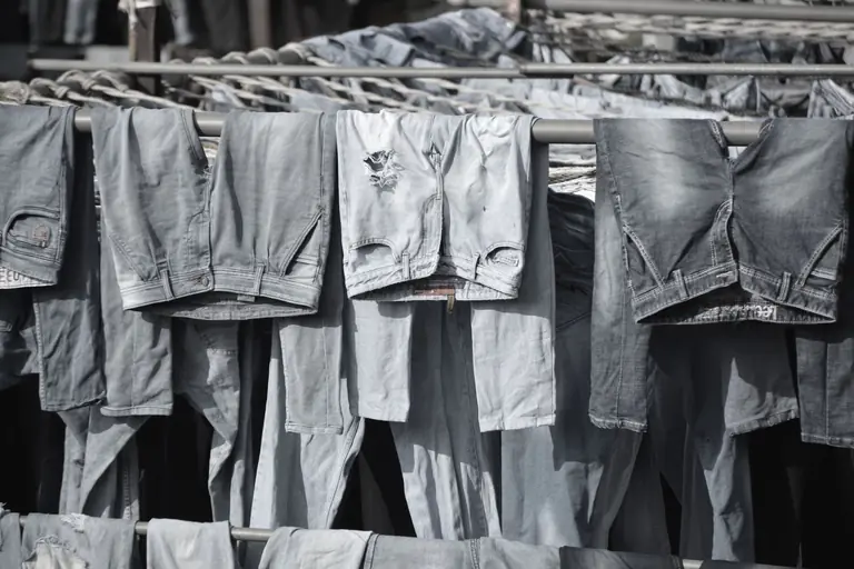 A collection of worn denim jeans hanging to dry on outdoor racks, creating a rustic and vintage vibe.
