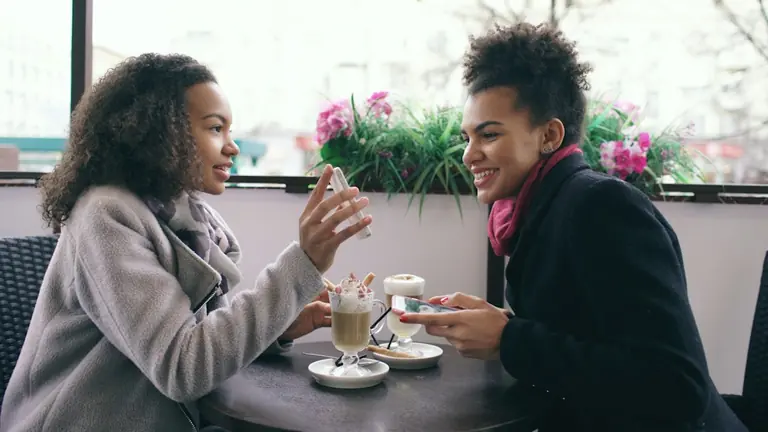 Two women talking at a cafe with drinks