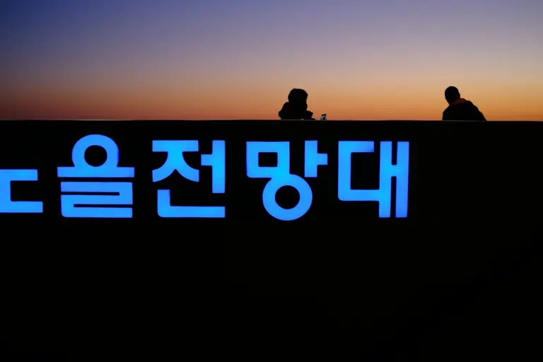 a couple of people sitting on top of a sign