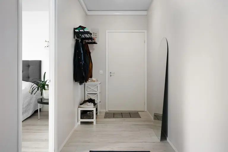 A minimalist hallway with white walls, modern decor, and simple furnishings.